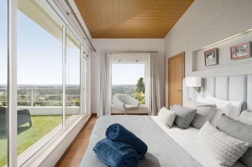 Un dormitorio con una gran cama blanca y una gran ventana. en Villa Mebahel - Boliqueime, en Boliqueime