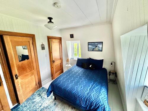 a bedroom with a bed with a blue comforter at Auberge musicale Pour un Instant in La Malbaie