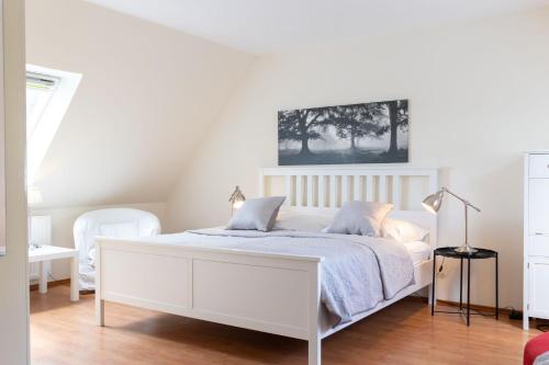 a white bedroom with a white bed with blue sheets at Gut Basthorst in Basthorst