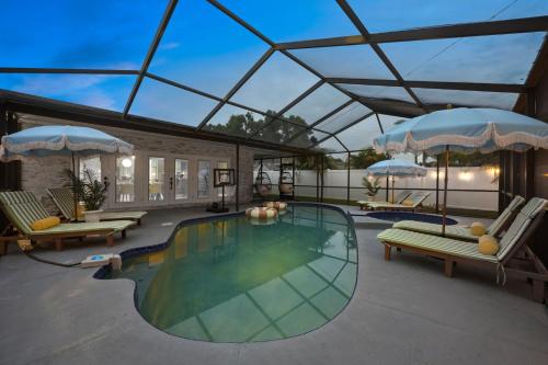 a swimming pool with chairs and umbrellas on a patio at Slashin' Staycation Pool Putt Putt Kids Playground in Seminole