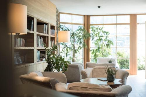 a living room with couches and a table and windows at Adler Spa Resort Balance in Ortisei