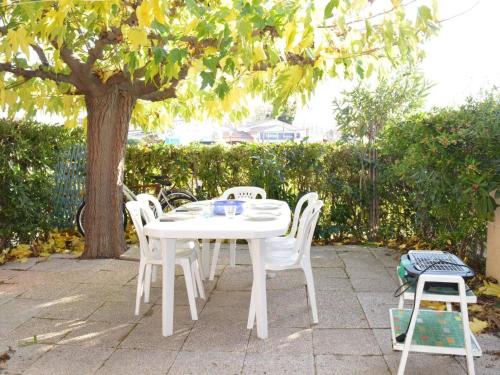 une table et des chaises blanches sous un arbre dans l'établissement Maison bord de mer 8 pers. avec terrasse, parking privé, animaux acceptés, ménage inclus - FR-1-225D-616, à Saint Cyprien Plage
