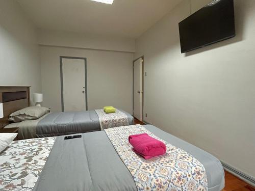 a bedroom with two beds and a flat screen tv at Depto calle huérfanos, Santiago in Santiago