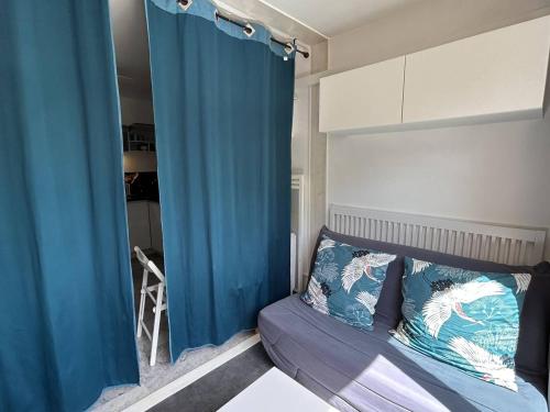 - une chambre avec un rideau bleu et un lit dans l'établissement Studio climatisé à 2 pas de la plage, loggia, parking privé - Bormes-les-Mimosas - FR-1-251-828, à Bormes-les-Mimosas