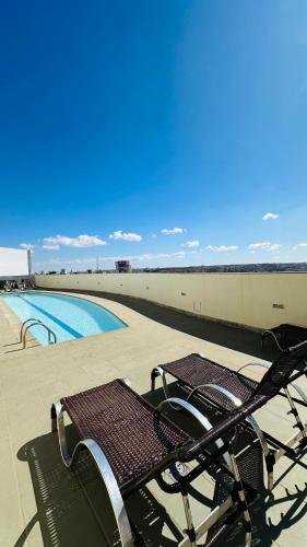 a couple of benches sitting next to a swimming pool at Quarto Mobiliado no Hotel Go Inn Taguatinga com Wi-Fi, Ar Condicionado e Estacionamento Grátis in Brasilia