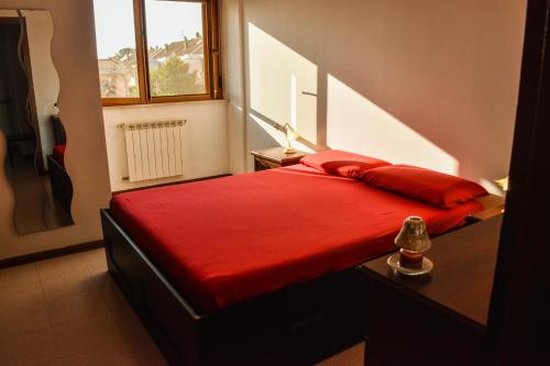 a red bed in a small room with a window at Al Delfino Blu in Aurelia