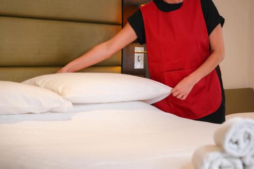 a woman in a red apron standing next to a bed at Coach & Horses Hotel in Cardiff