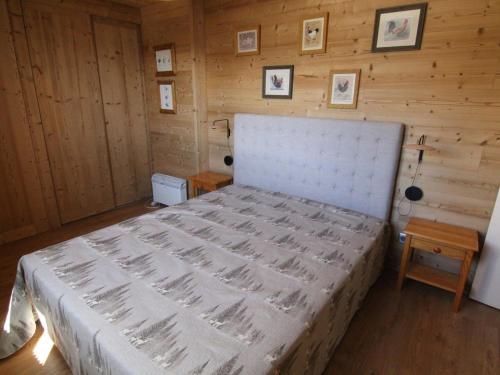 - une chambre avec un grand lit dans un mur en bois dans l'établissement Appartement cosy 3 pièces, 6 pers, pistes et centre à proximité, balcon sud, animaux OK - Huez - FR-1-405-77, à L'Alpe-d'Huez