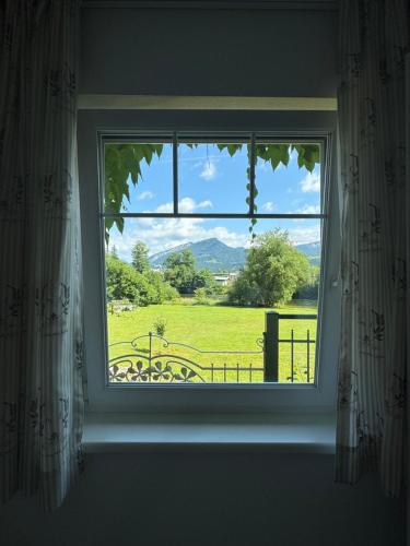 a window with a view of a green field at Landhaus HALLSTATT FEELING - Apartment - Self Check-in in Bad Goisern