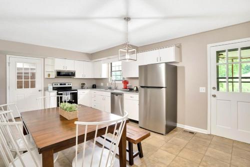 a kitchen with a table and a stainless steel refrigerator at Country Lane Cottage- privacy & quiet neighborhood in Rossville
