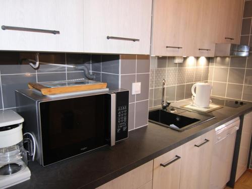 une cuisine avec un micro-ondes et un évier dans l'établissement Studio confortable aux Saisies pour 4 personnes avec balcon et cuisine équipée - FR-1-594-127, à Hauteluce