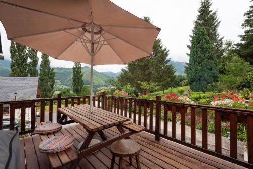 a wooden deck with a table and an umbrella at Chalet cosy Vallée d’Aspe in Accous