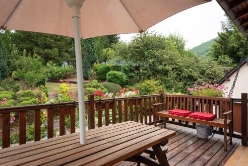 a wooden deck with a bench and an umbrella at Chalet cosy Vallée d’Aspe in Accous