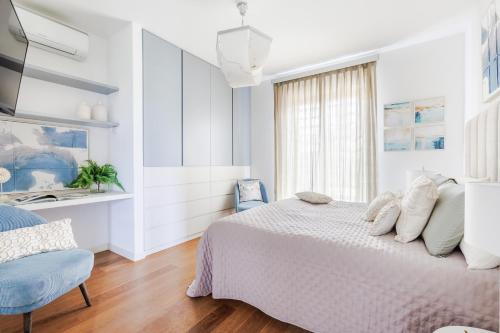 a white bedroom with a bed and a chair at The Secret Escape Villa in Sant' Alessio
