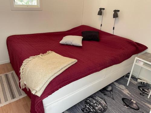 a bedroom with a bed with a red comforter at Gäststuga i mysiga Sparreholm in Sparreholm