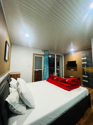 a bedroom with a bed with a red blanket on it at ANURAG HOMESTAY in Kurseong