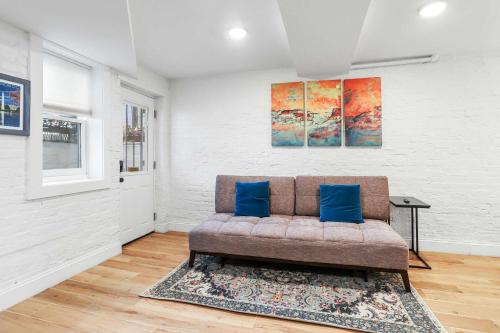 a couch with two blue pillows in a living room at Sojourn Charming Lower Level Studio - Capitol Hill in Washington, D.C.