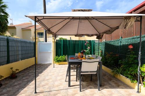 a table and chairs under an umbrella on a patio at Bungalow with Terrace BBQ Pool in Maspalomas in Maspalomas