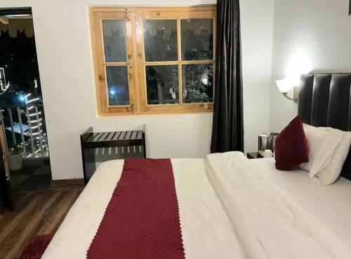 a bedroom with a white bed with a window at The Boho Woods Resort in Nainital