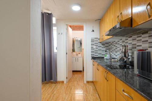 a kitchen with wooden cabinets and black counter tops at Bungalow with Terrace BBQ Pool in Maspalomas in Maspalomas