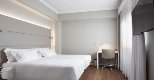 a bedroom with a large white bed and a desk at NH Las Palmas Playa las Canteras in Las Palmas de Gran Canaria