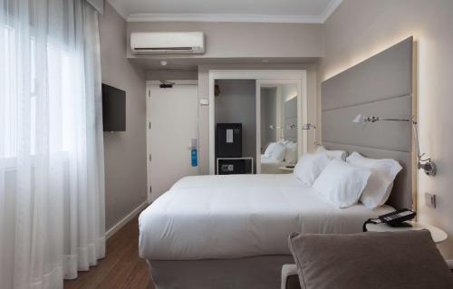 a bedroom with a large white bed and a window at NH Las Palmas Playa las Canteras in Las Palmas de Gran Canaria