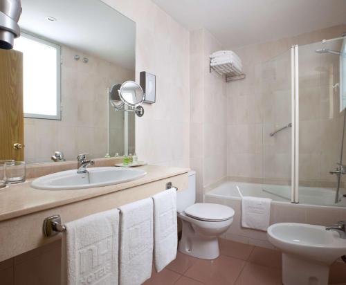 a bathroom with a sink and a toilet and a tub at NH Las Palmas Playa las Canteras in Las Palmas de Gran Canaria