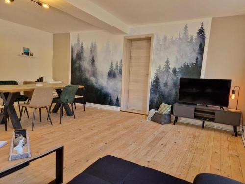 a living room with a tv and a table with chairs at 3 Zimmer Ferienwohnung Harter Brocken in Sankt Andreasberg