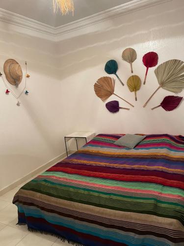 a bedroom with a bed with colorful sheets and hats on the wall at Tata Katy Banana Guesthouse in Aourir