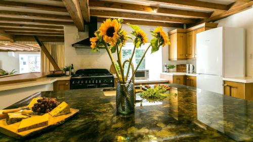 a vase with sunflowers on a counter in a kitchen at Felin Hen in Menai Bridge