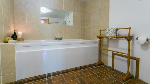 a bathroom with a white tub and a mirror at Felin Hen in Menai Bridge
