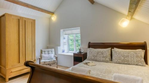 a bedroom with a bed and a chair and a window at Felin Hen in Menai Bridge
