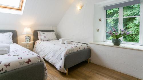 a bedroom with two beds and a window at Felin Hen in Menai Bridge