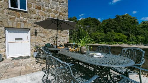 a table and chairs with an umbrella on a patio at Felin Hen in Menai Bridge
