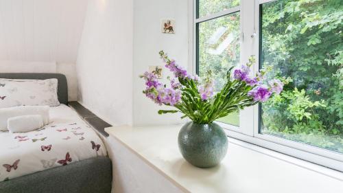 a vase filled with purple flowers sitting on a window sill at Felin Hen in Menai Bridge