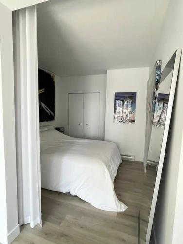 a bedroom with a white bed and a mirror at Loft moderne au coeur de Montreal in Montréal