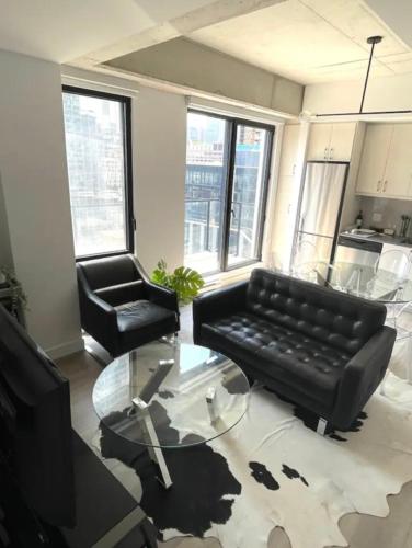 a living room with a black couch and a glass table at Loft moderne au coeur de Montreal in Montréal