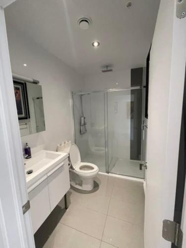 a white bathroom with a toilet and a shower at Loft moderne au coeur de Montreal in Montréal