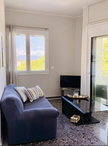 a living room with a blue couch and a glass table at Sea breeze in Nafpaktos