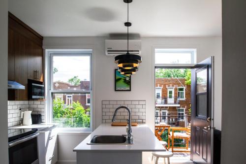a kitchen with a sink and two windows at Appartement cozy et lumineux avec parking in Montréal
