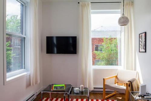 a living room with a tv and two windows at Appartement cozy et lumineux avec parking in Montréal