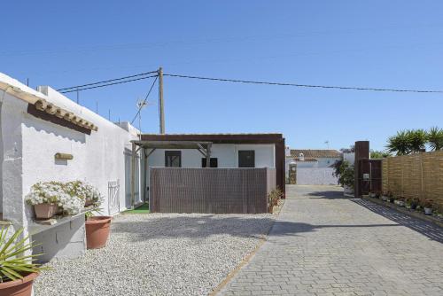 a white house with a gate and a driveway at Finca Abril 1 Piscina Compartida in Conil de la Frontera