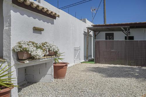 a white house with potted plants on the side of it at Finca Abril 1 Piscina Compartida in Conil de la Frontera
