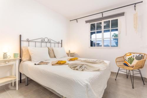 a white bedroom with a bed and a chair at El Cuarto De Moza in Tinajo