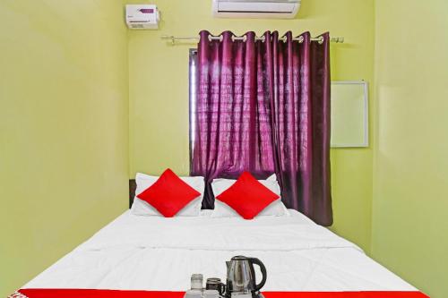 a bedroom with a bed with red pillows and a window at Hotel O Manjiri Restaurant & Lodging in Nagpur