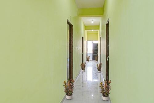 a hallway with green walls and potted plants at Hotel O Manjiri Restaurant & Lodging in Nagpur