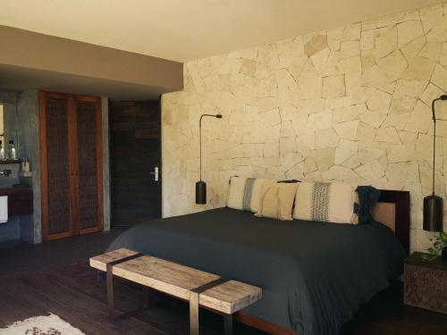 a bedroom with a bed and a stone wall at BE Destination Tulum in Tulum