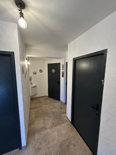 a hallway with two black doors and a tile floor at Gite Clé des Champs in Montenois