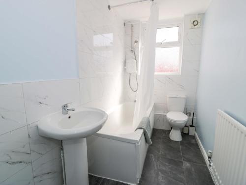 a white bathroom with a sink and a toilet at Bryn Hyfryd in Conwy