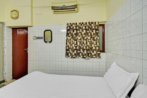 a room with a bed and a window and a clock at Hotel O Dream Palace Guest House Near Marina Beach in Chennai